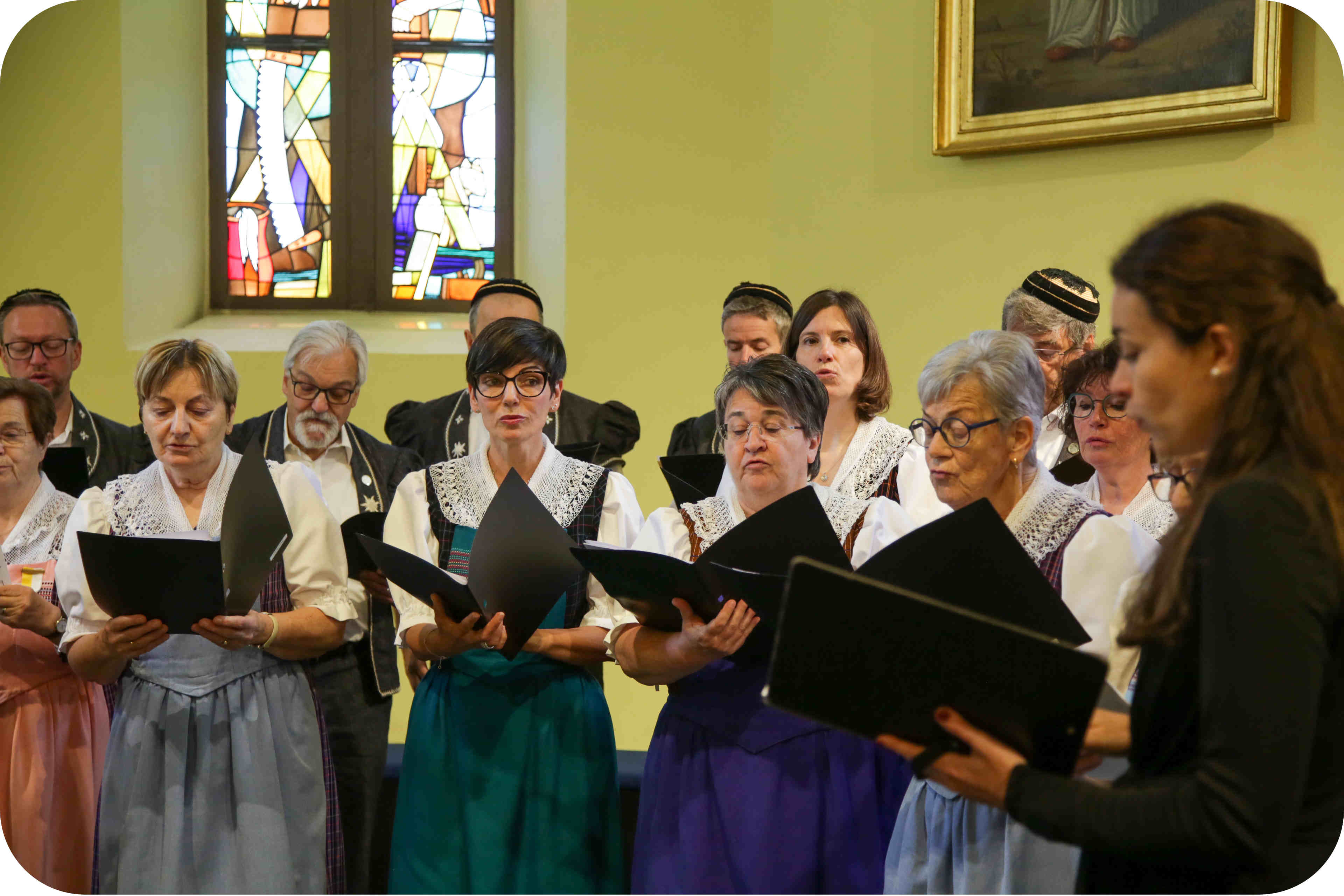 Photo d'une partie du chœur L’écho de la Sarine, en costume, lors d'une prestation On voit une partie du chœur mixte l’écho de la Sarine, en costume, lors de la remise de Médailles Bene Merenti en l'église de Rossens